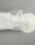 White powder spilling out of a rectangular container on a gray surface