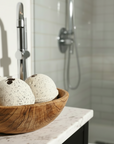 Wooden bowl with bath bombs on a bathroom counter
