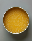 Metal cake pan with Turmeric lip scrub in a tin on a gray background