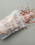 Packaged bath salts with some spilled on a gray surface